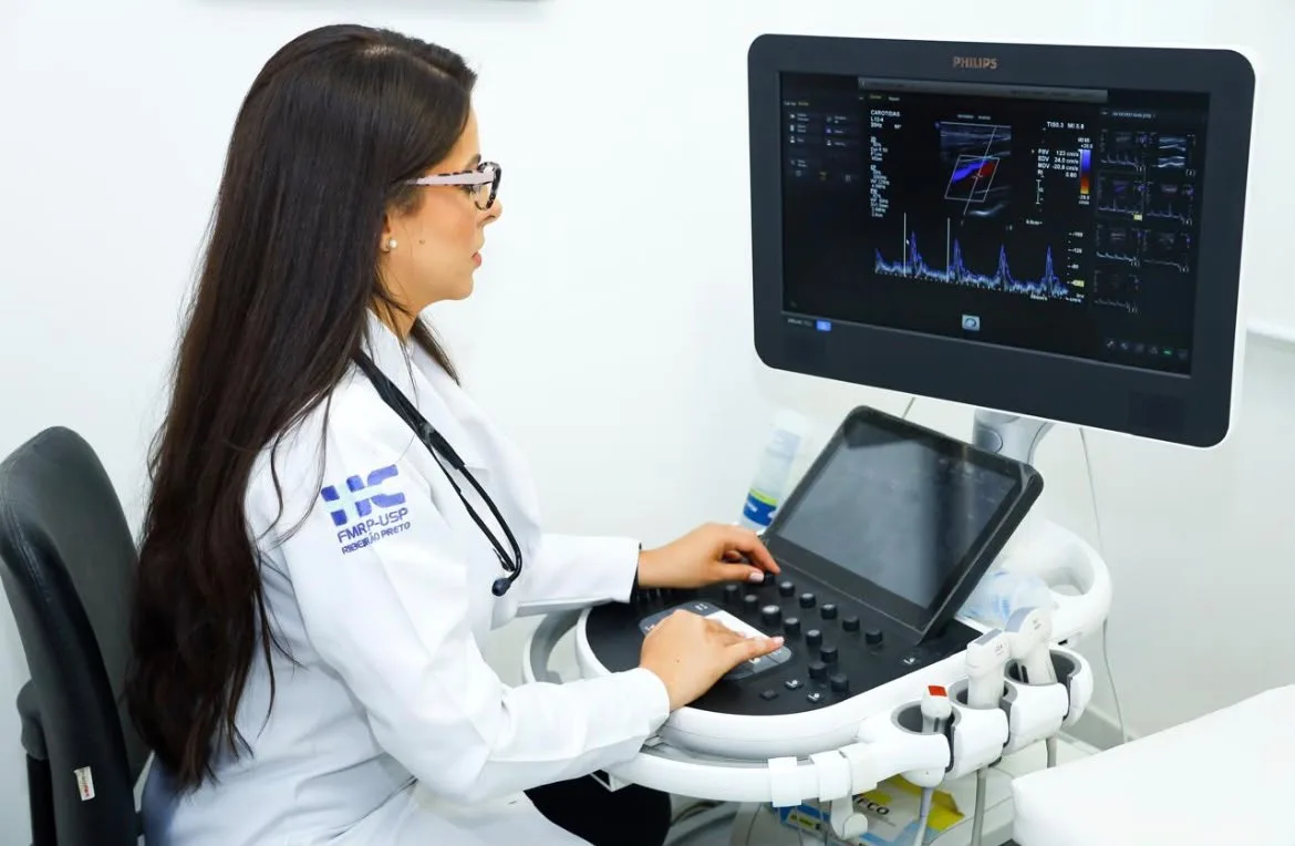 Dra. Roberta sentada ao aparelho de ecocardiograma analisando imagens